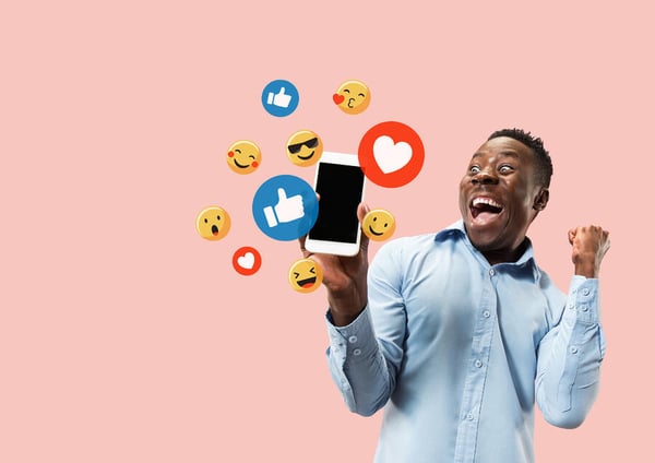 Social media interactions on mobile phone. Internet digital marketing, Chating, commenting, liking. Smiles and icons above smartphone screen, that holding by young man on pink studio background
