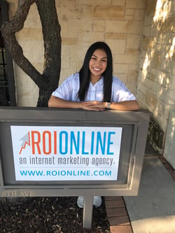Monica smiling in front of the ROI Online sign 