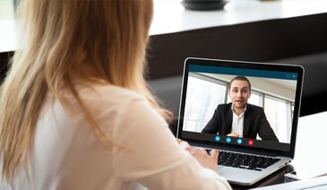 From behind shot of woman having video conference with man in business suit